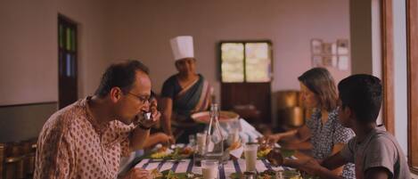A group of people dining at a table with a striped tablecloth, surrounded by various dishes and drinks.