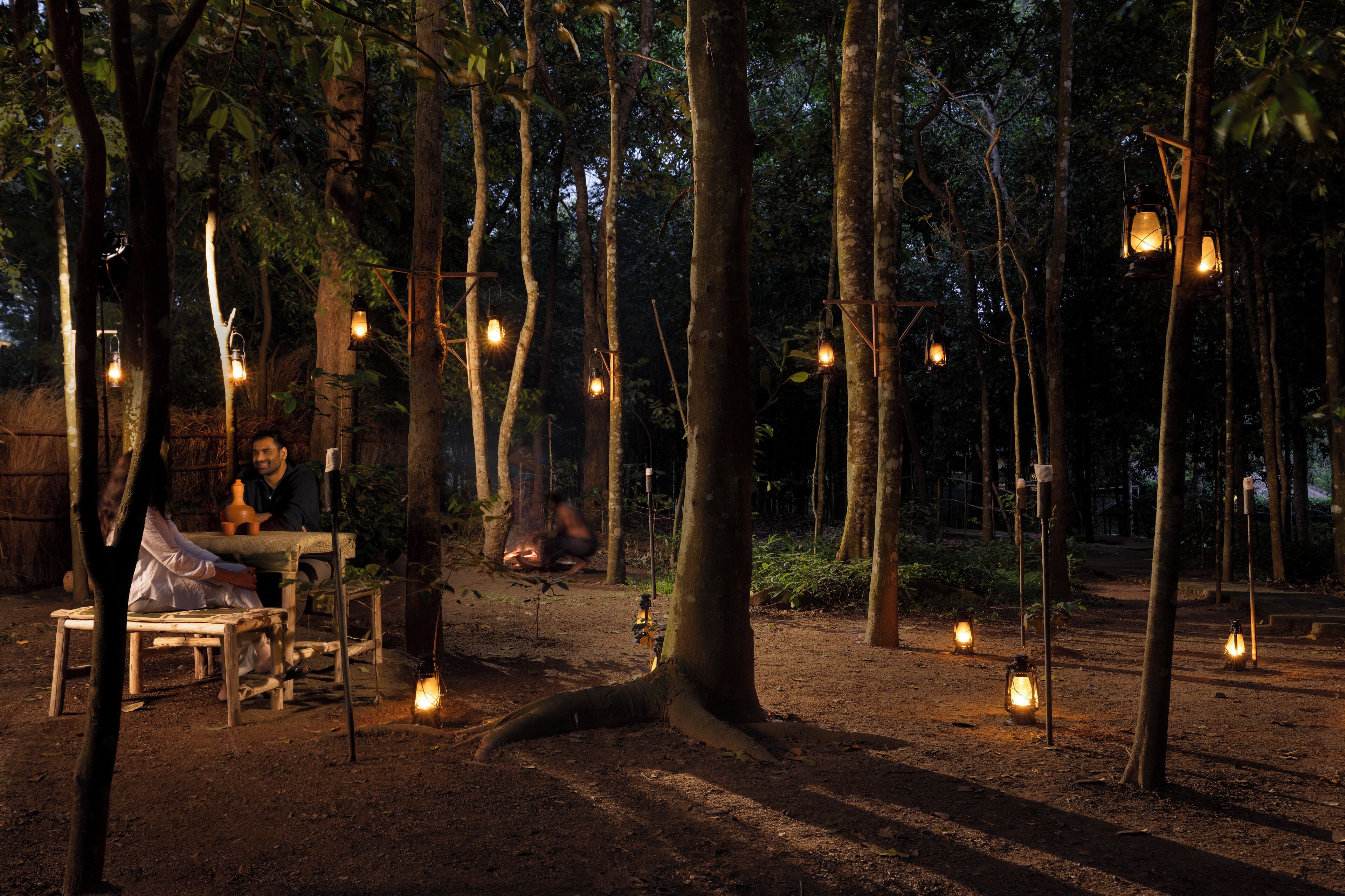 A rustic outdoor setting with wooden furniture and hanging lanterns, suggesting a campsite or outdoor dining area.