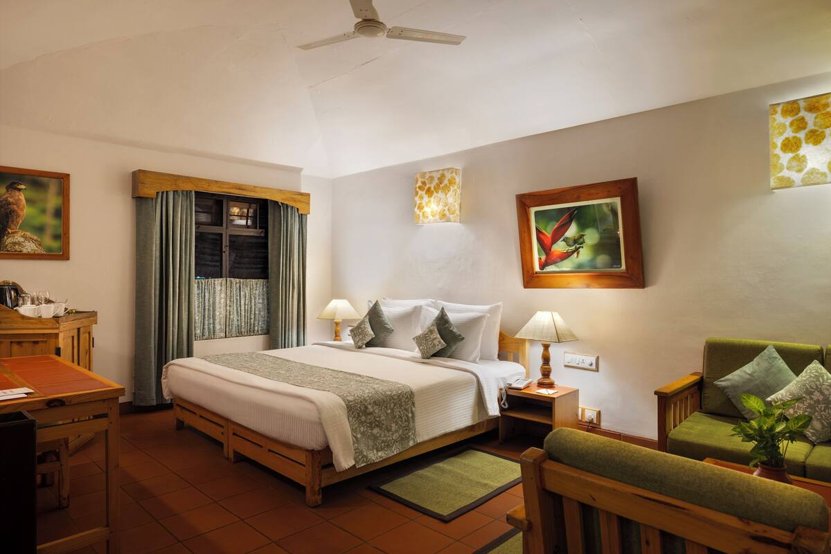 A hotel room with a bed, a desk, a chair, a nightstand, and a green sofa.