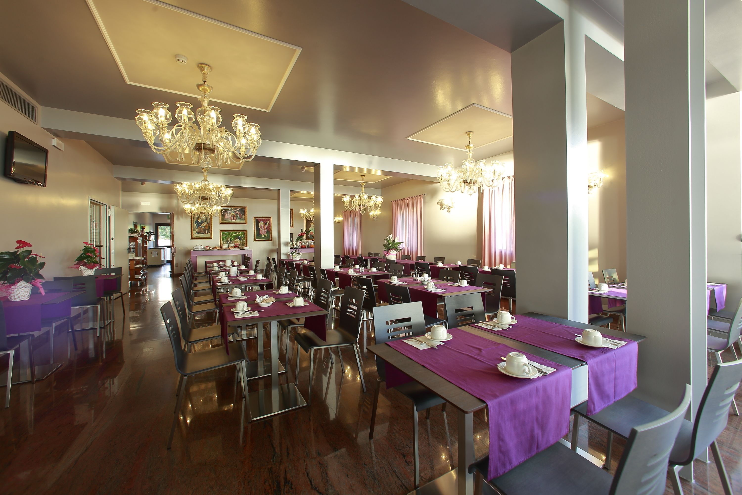 Un comedor amplio con varias mesas, sillas y candelabros.
