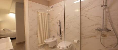 Un baño moderno con ducha de vidrio, un bidé y un inodoro.