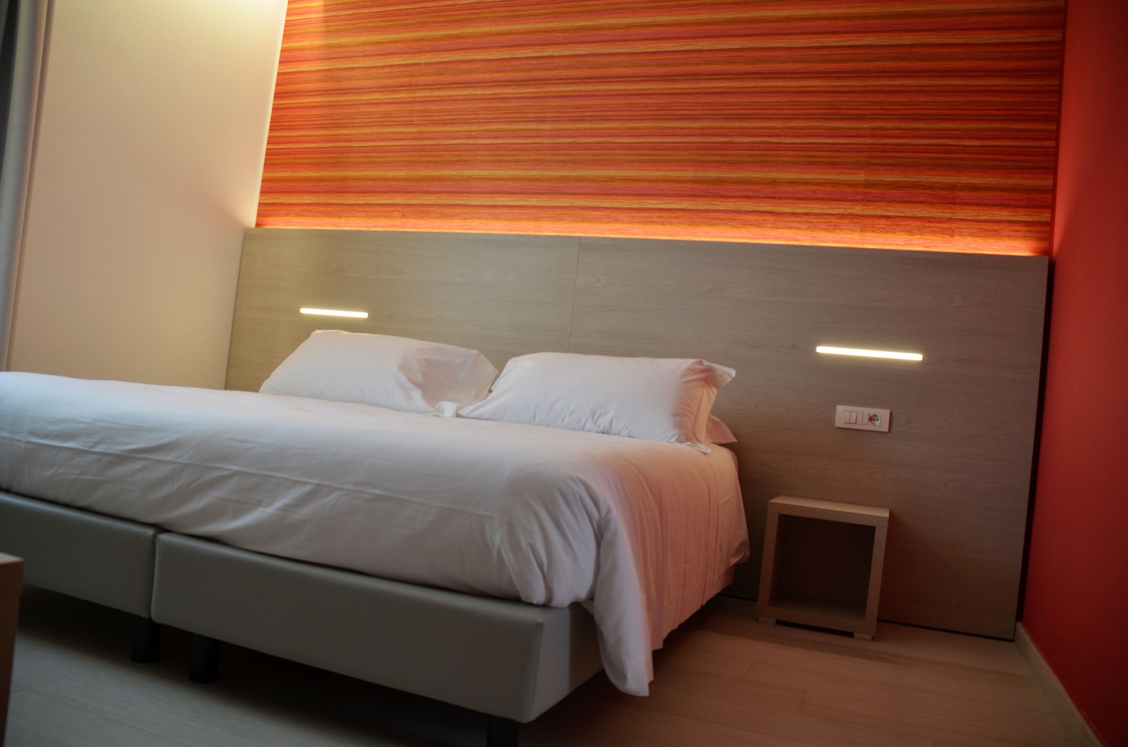 Un dormitorio moderno con cama, mesitas de noche y una pequeña mesita auxiliar.