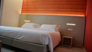 Un dormitorio moderno con cama, mesitas de noche y una pequeña mesita auxiliar.