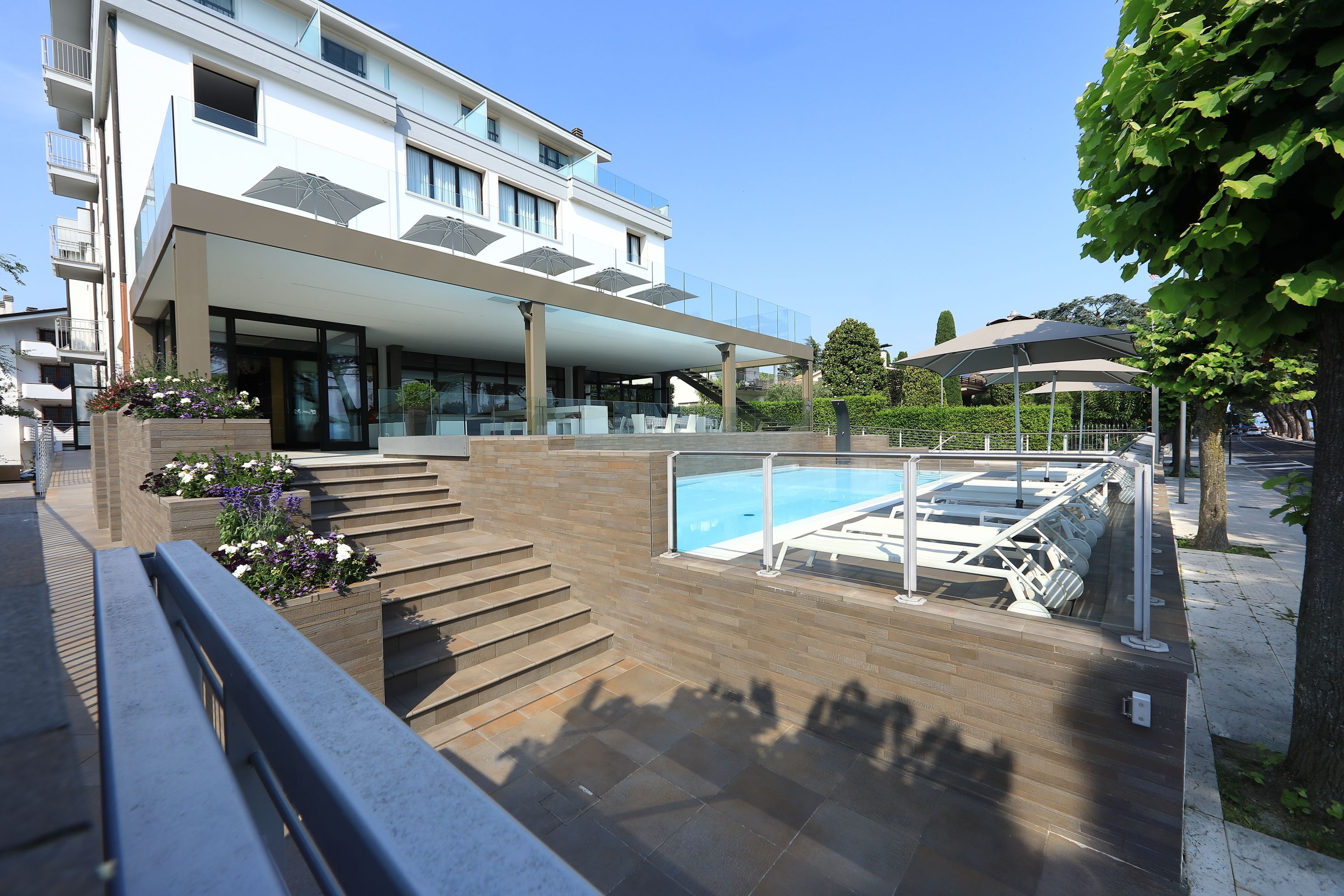 A modern building with a pool area, outdoor seating, and a staircase leading to the entrance.