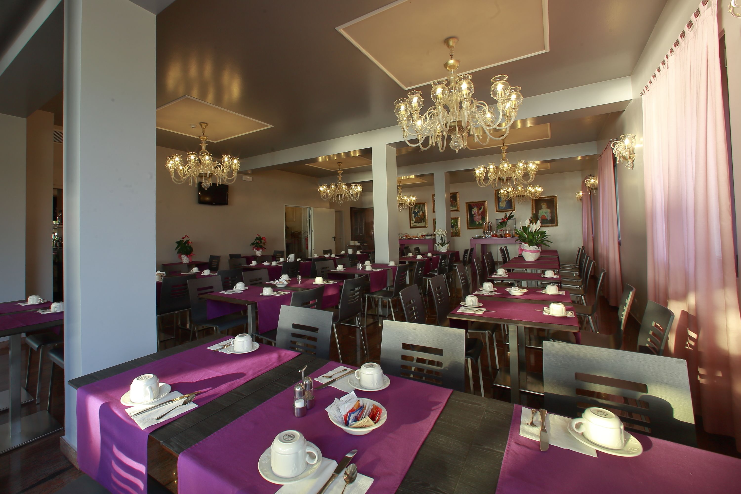 A spacious dining area with multiple tables, each set with white tableware and purple tablecloths.