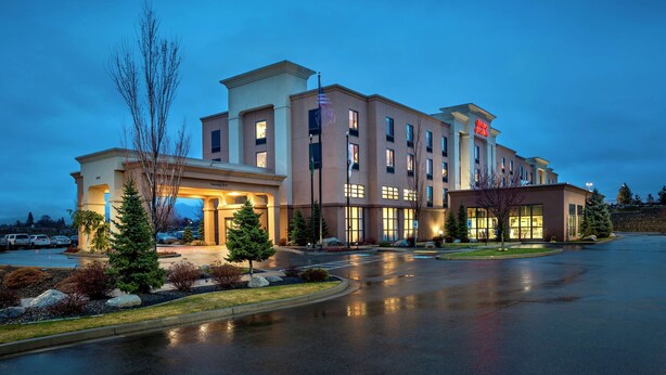 A multi-story hotel with a central entrance, parking area, and landscaped surroundings. - Hampton Inn & Suites Spokane Valley (Spokane Valley)