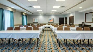 A conference room with tables and chairs, patterned carpet, and framed artwork on the walls.