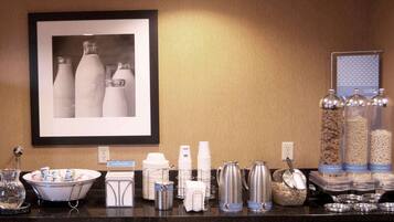 A hotel breakfast bar with various food and drink options, including cereal, milk, and coffee.