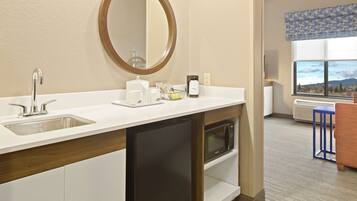A modern bathroom with a sink, mirror, and built-in microwave.