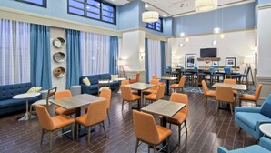 A hotel lobby with a dining area, sofas, and a TV screen. - Hampton Inn & Suites Spokane Valley (Spokane Valley)
