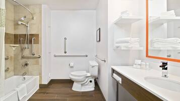 A modern bathroom with a bathtub, shower, toilet, and vanity with a mirror.