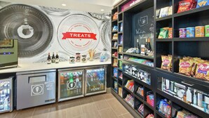 A self-service beverage station with a 'TREATS' sign, refrigerated drink dispensers, and shelves stocked with snacks and condiments. - Hampton Inn & Suites Spokane Valley (Spokane Valley)