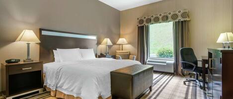 Une chambre d’hôtel avec un grand lit, deux tables de chevet avec des lampes, un bureau avec une chaise et une grande fenêtre avec des rideaux.