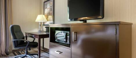 Une chambre d’hôtel équipée d’un téléviseur à écran plat fixé à un meuble, d’un bureau avec une lampe et d’un fauteuil de bureau moderne.