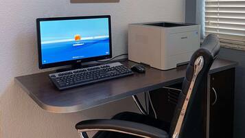 Een bureau voor een business center met een computer, toetsenbord, muis en een printer.