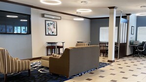 A modern lobby with a sofa, chairs, a table, and a computer desk.