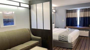 Une chambre d’hôtel avec un lit, un canapé, une fenêtre avec des rideaux et une œuvre d’art accrochée au mur.