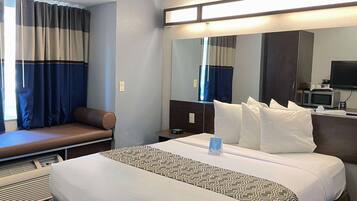 Una habitación de hotel con cama, zona de estar, escritorio con computadora y televisor.
