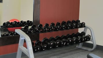A gym with a mirrored wall, a red exercise ball, and a rack of dumbbells.