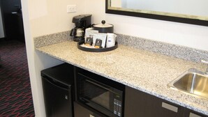 Unidad de cocina pequeña con cafetera, microondas y zona para secar trastes.