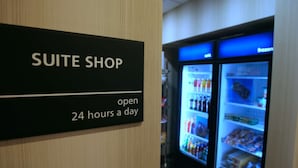 Señal para Suite Shop, abierto las 24 horas, al lado de un expositor refrigerado.