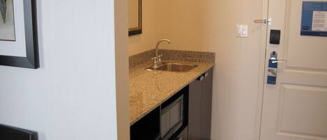 A compact kitchen with a granite countertop, stainless steel sink, and a built-in oven.