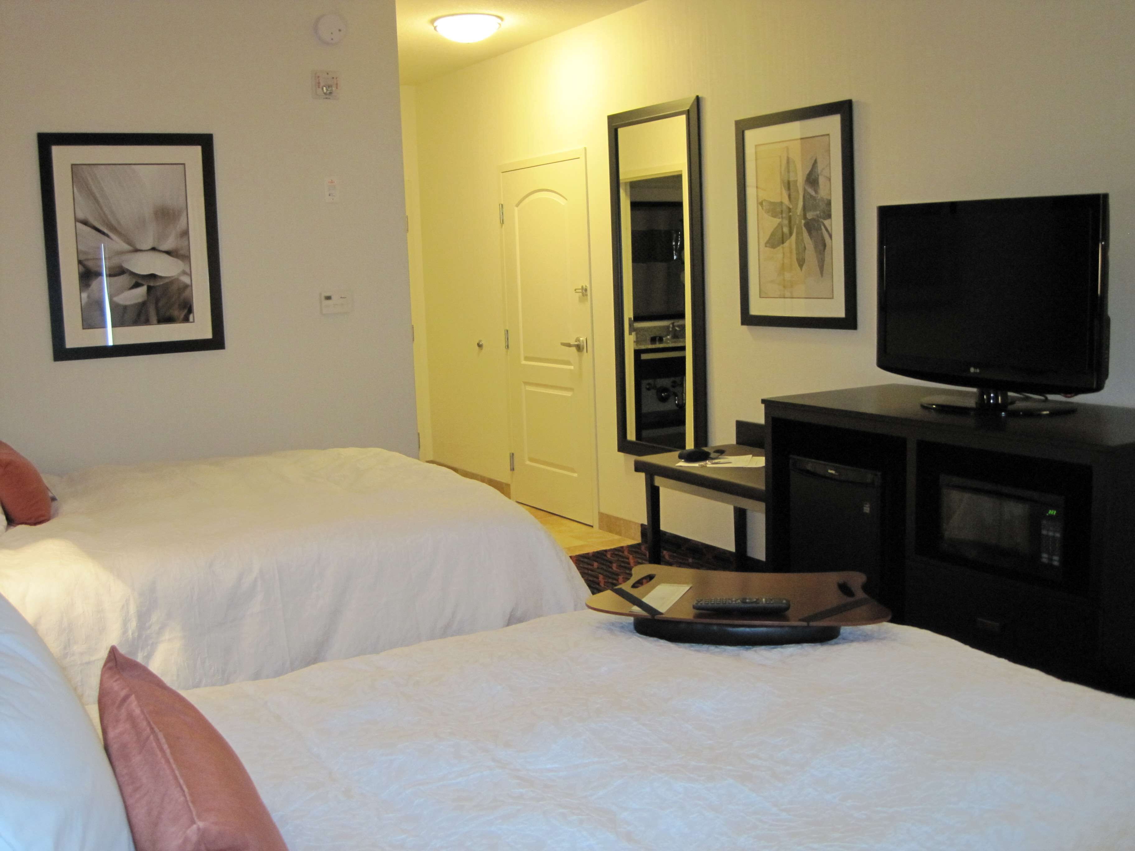 A hotel room with two beds, a TV, a desk, and a microwave.