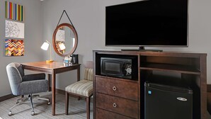 A hotel room with a wooden desk, a chair, a television, a microwave, and a minibar. - Hampton Inn Farmington (Farmington)