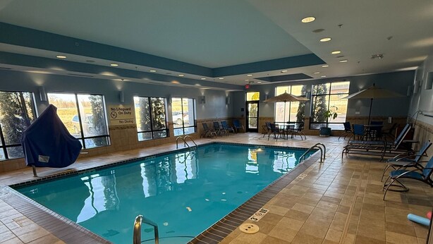 An indoor swimming pool with clear water, surrounded by lounge chairs and a tiled floor. - Hampton Inn Farmington (Farmington)