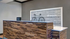 A reception desk with a wooden panel design, a bicycle mounted on the wall, and a sign reading "Hilton Honors". - Hampton Inn Farmington (Farmington)