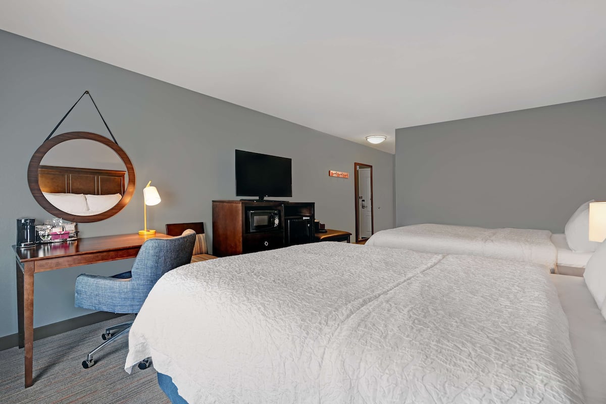 A hotel room with a bed, a desk with a chair, a television, and a microwave.