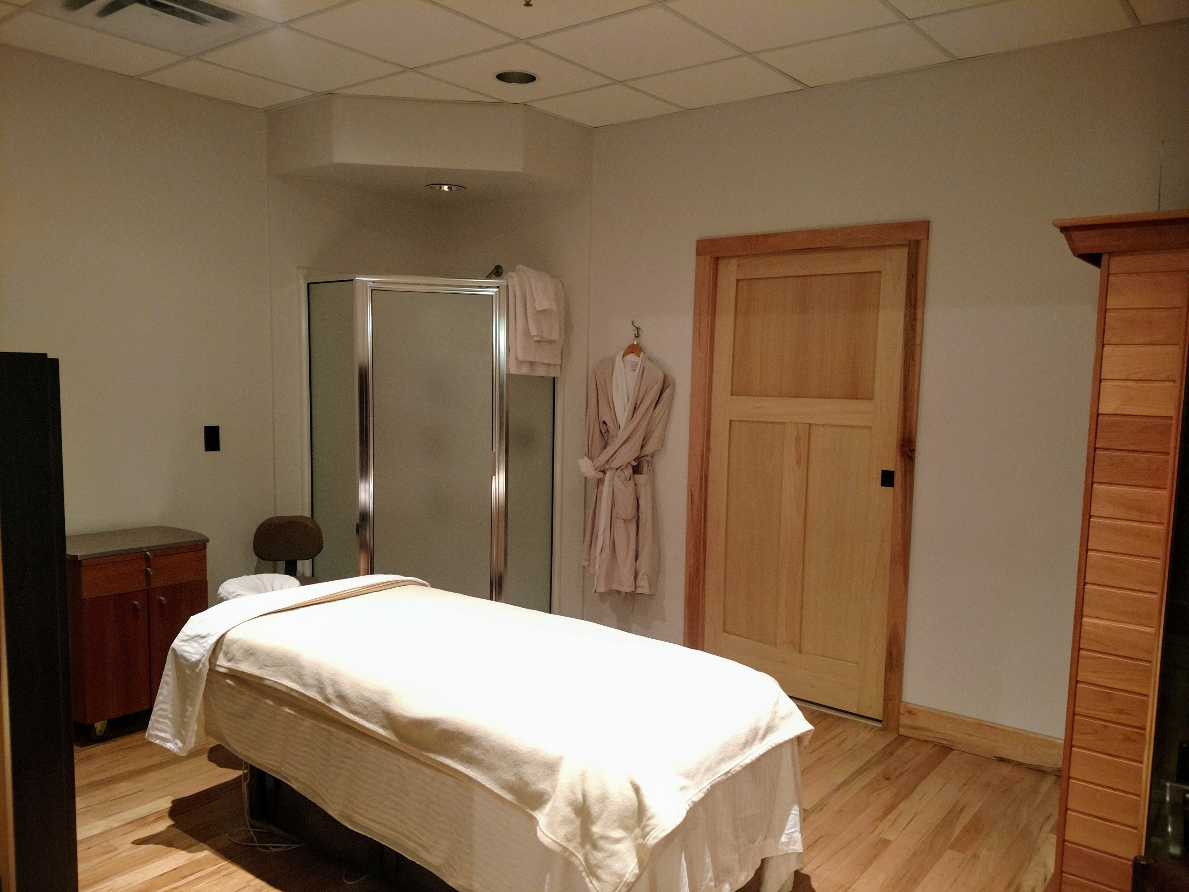 A bedroom with a bed, a wooden wardrobe, a wooden door, and a mirror.