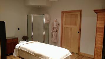 A bedroom with a bed, a wooden wardrobe, a wooden door, and a mirror.