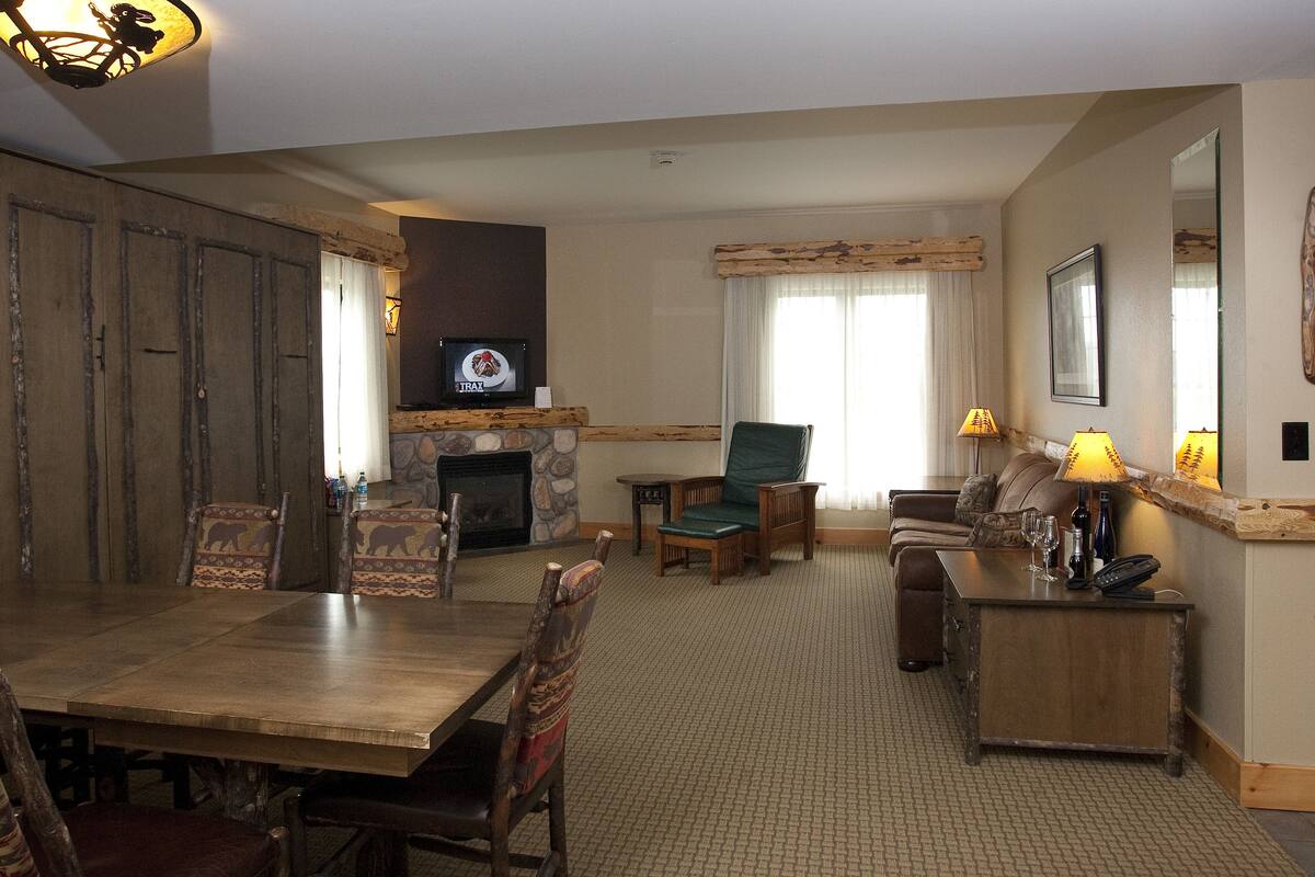A spacious living room with a wooden dining table, comfortable seating, a fireplace, and a television.
