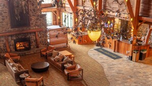A spacious lobby with a stone fireplace, leather seating, a wooden reception desk, and a chandelier.