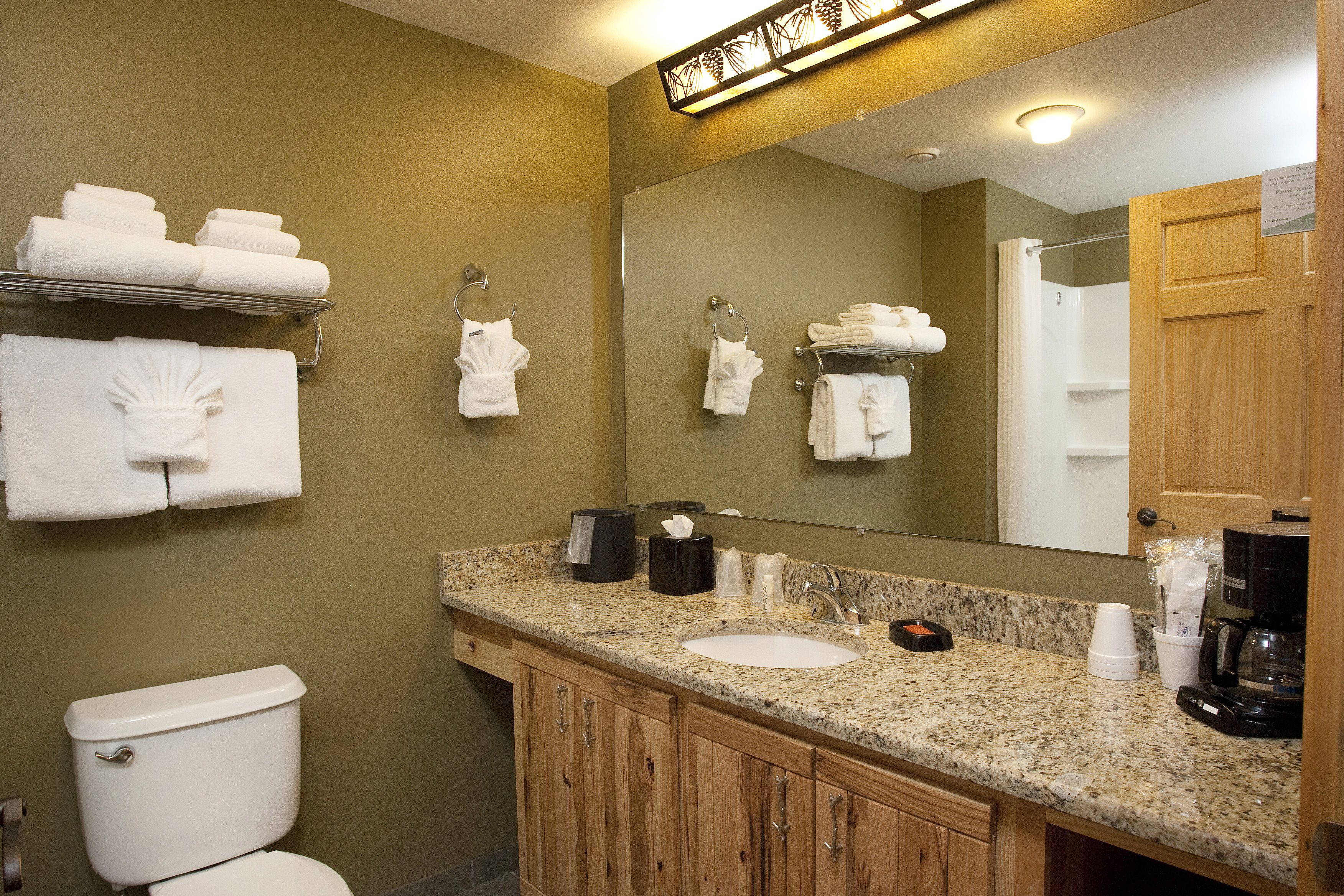Une salle de bain avec un lavabo, un miroir et des serviettes rangées sur un porte-serviettes.