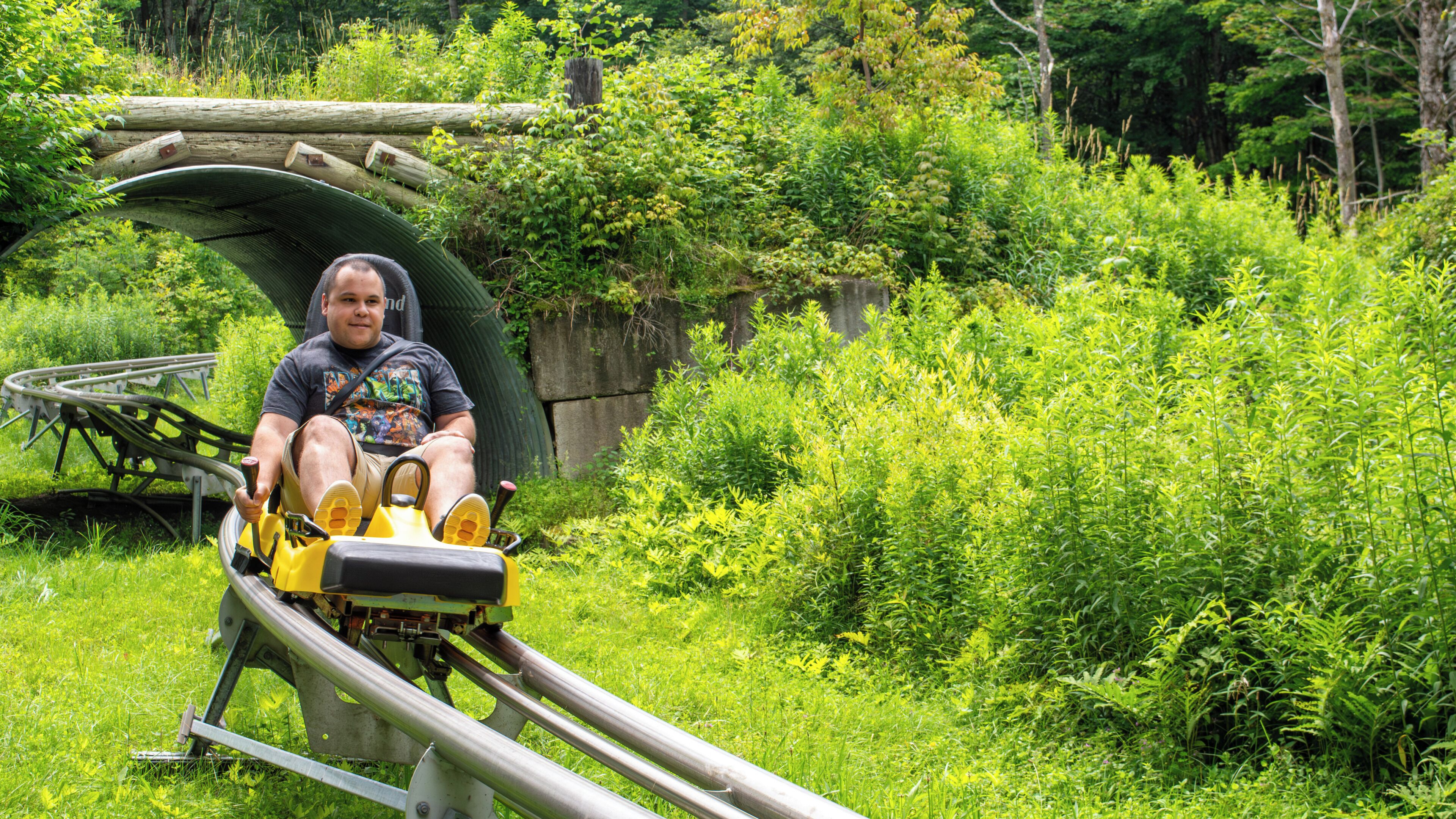 A person seated on a yellow and black roller coaster track.