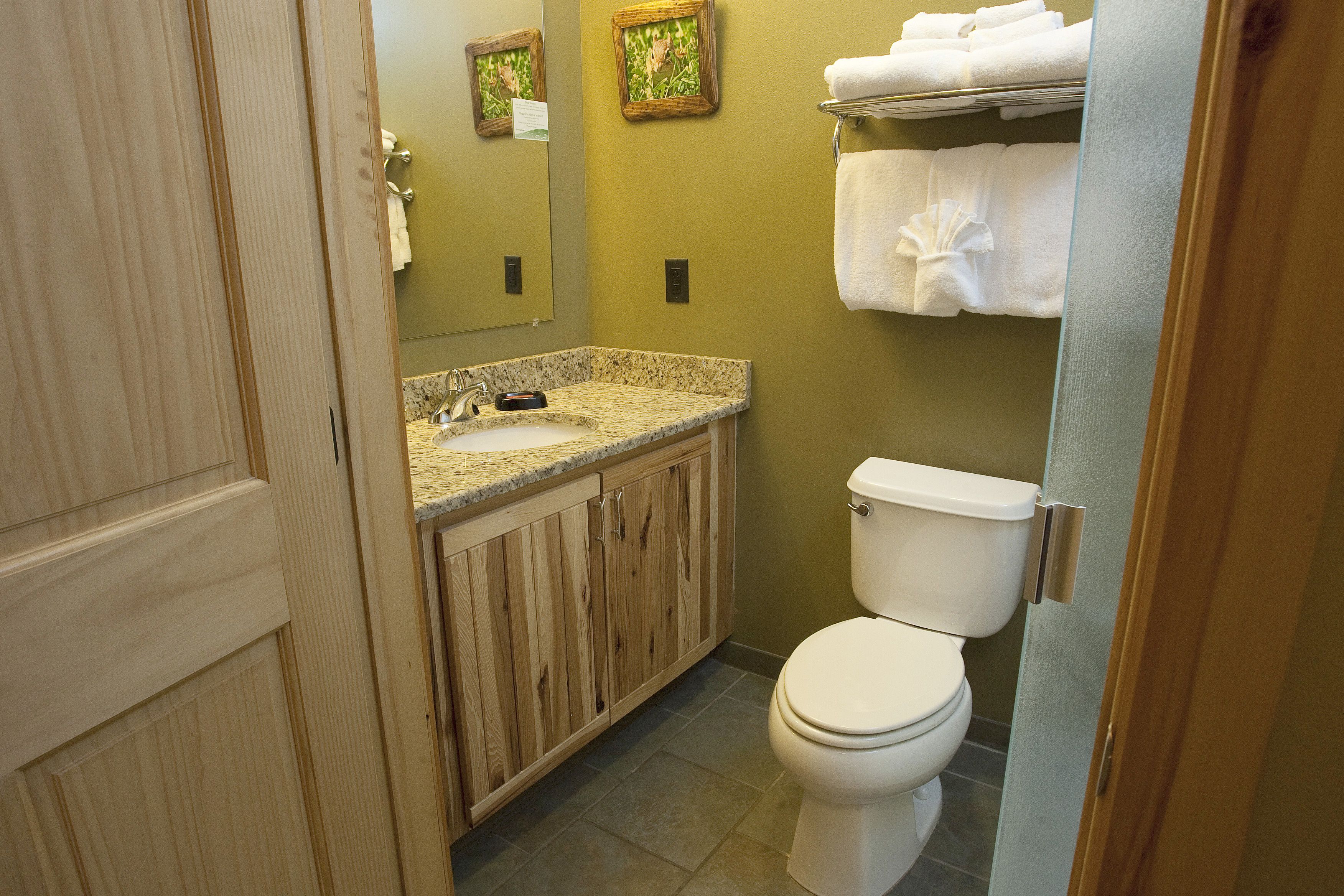 A bathroom with a wooden vanity, a sink, a toilet, and a towel rack with towels.