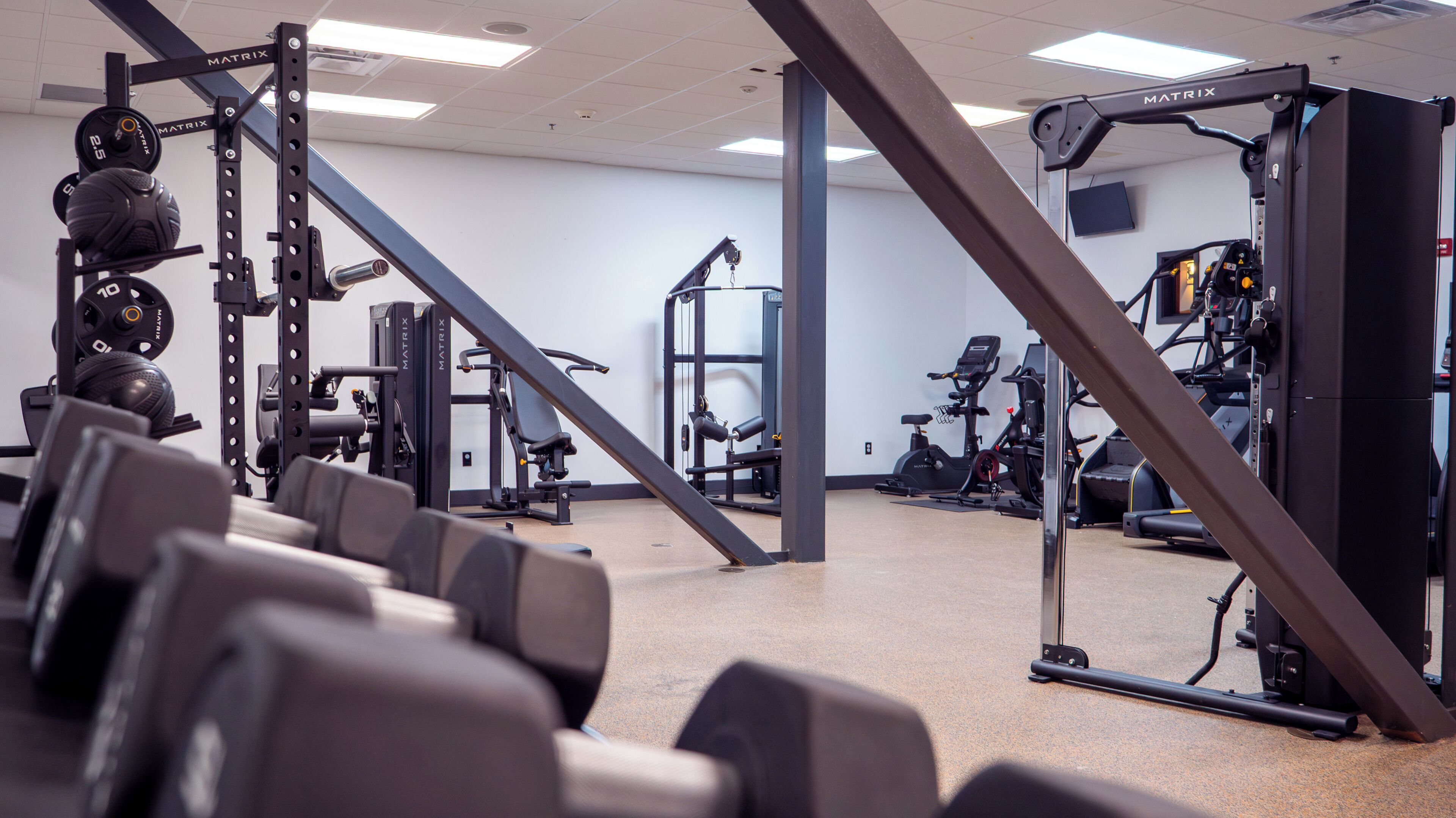 Une salle de sport équipée de matériel de musculation, de machines d’exercice et d’un miroir qui reflète l’espace.