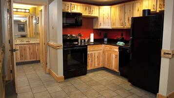 A kitchen with wooden cabinets, a black refrigerator, a microwave, and a stove.