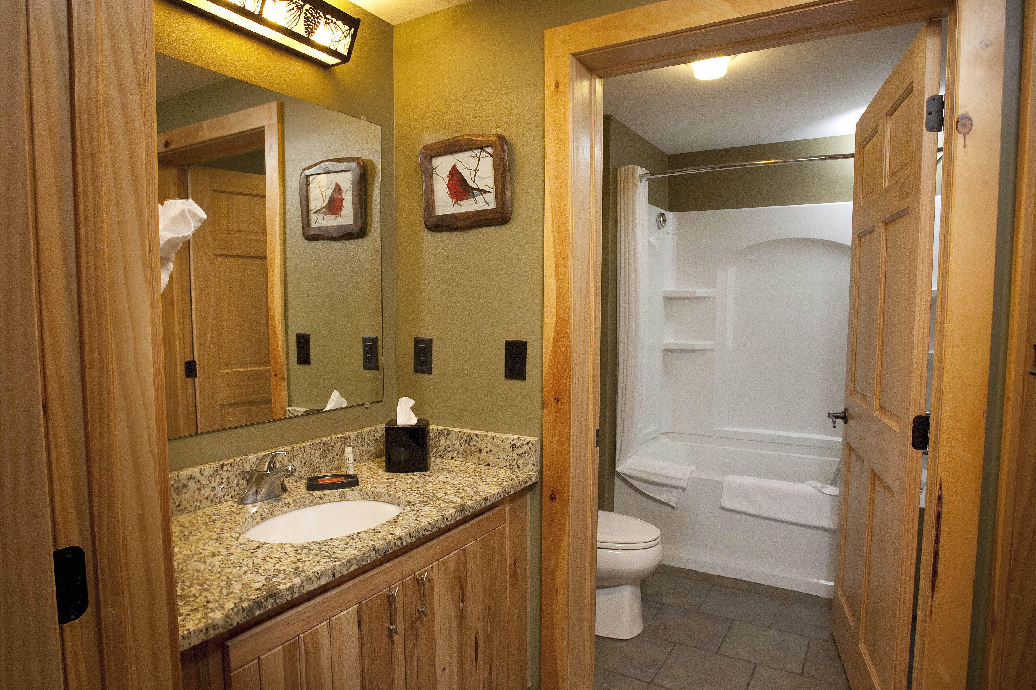 A bathroom with a wooden vanity, a sink, a toilet, and a shower.