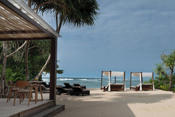 Un salón junto a la playa con asientos al aire libre y vista al océano.