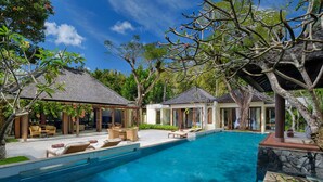 A pool area with lounge chairs and a covered seating area.