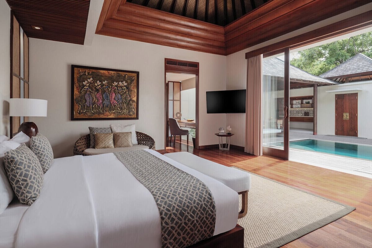 Ein geräumiges Schlafzimmer mit einem großen Bett, einem Fernseher und Blick auf einen Swimmingpool.