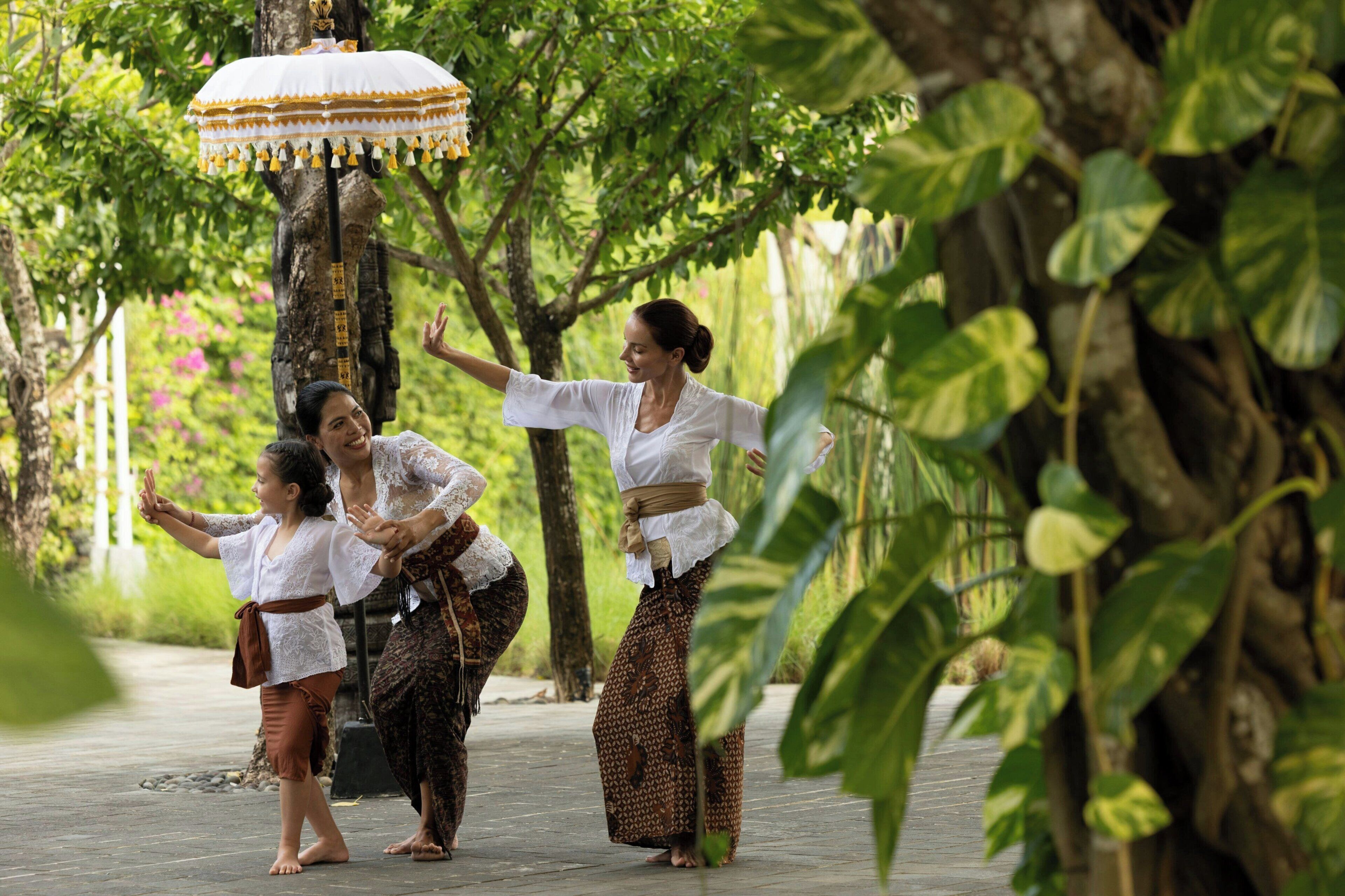 A traditional dance performance in an outdoor setting with a tree and a pathway.