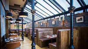 A restaurant with wooden booths, black columns, and a high ceiling with skylights. - Royal Oak Hotel (Betws-Y-Coed)