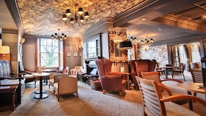 A cozy lounge area with wooden furniture, a fireplace, and a patterned ceiling. - Royal Oak Hotel (Betws-Y-Coed)