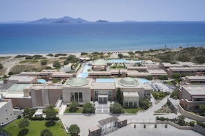 A resort with multiple buildings, a swimming pool, and a beach view.