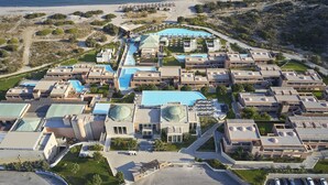 Luchtbeeld van een resort met meerdere gebouwen, een zwembad en een strand.