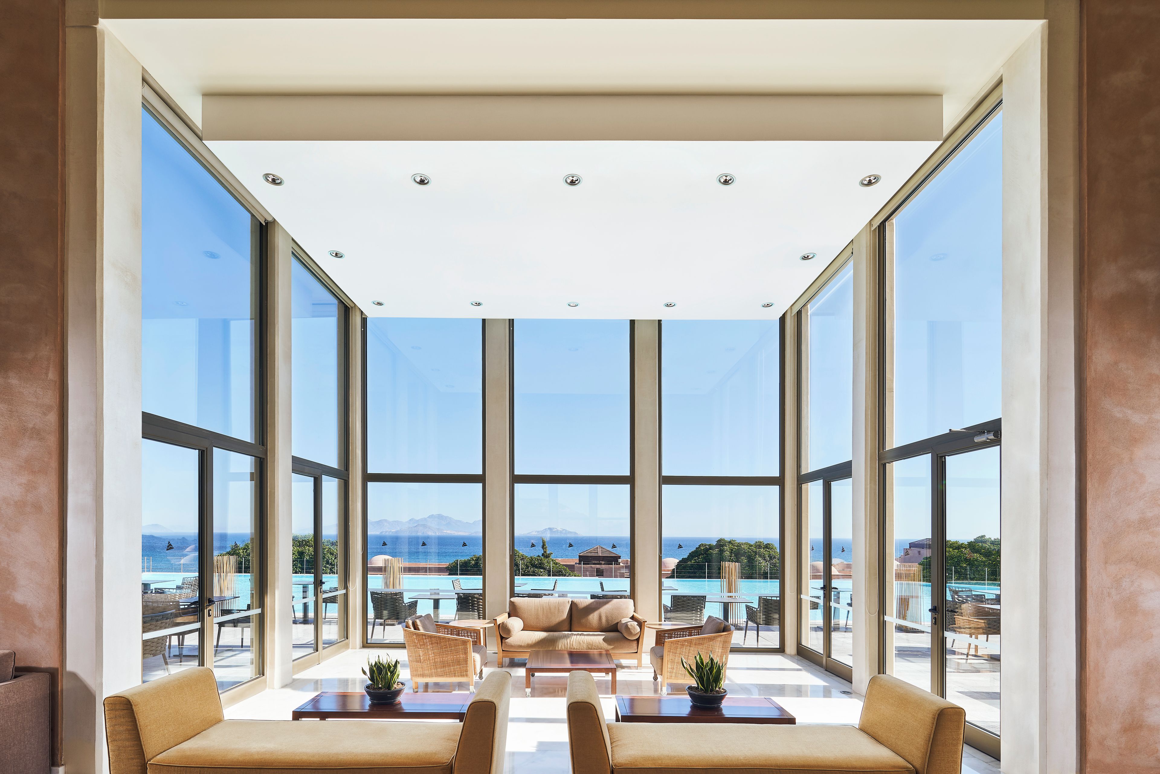 Un'ampia stanza con grandi finestre, un divano, un tavolino da caffè e vista sul mare.